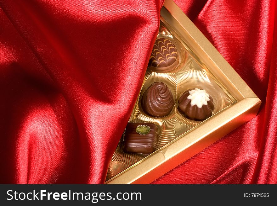 Golden chocolates box on red satin background