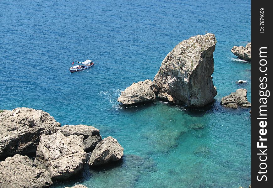 Boat at rocks of Mediterranean sea.