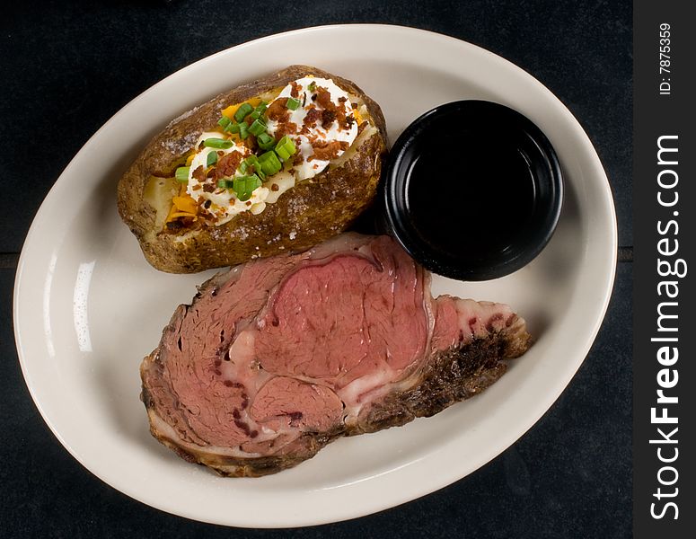 Medium rare steak with au jus and a baked potato. Medium rare steak with au jus and a baked potato