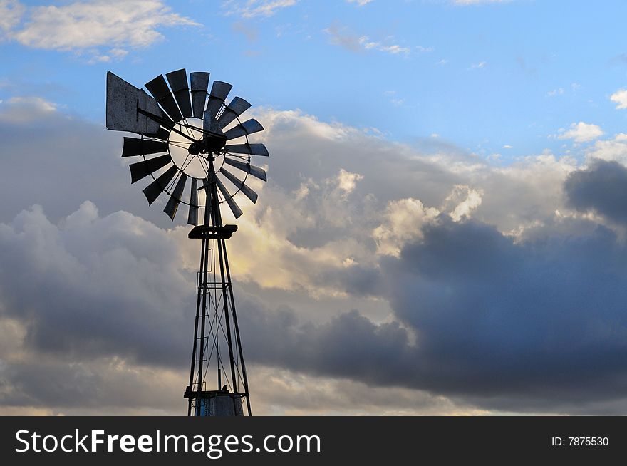 Image of a windmill on cloudy sky on sunset