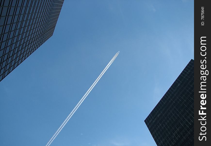 The plane between skyscrapers in the blue sky