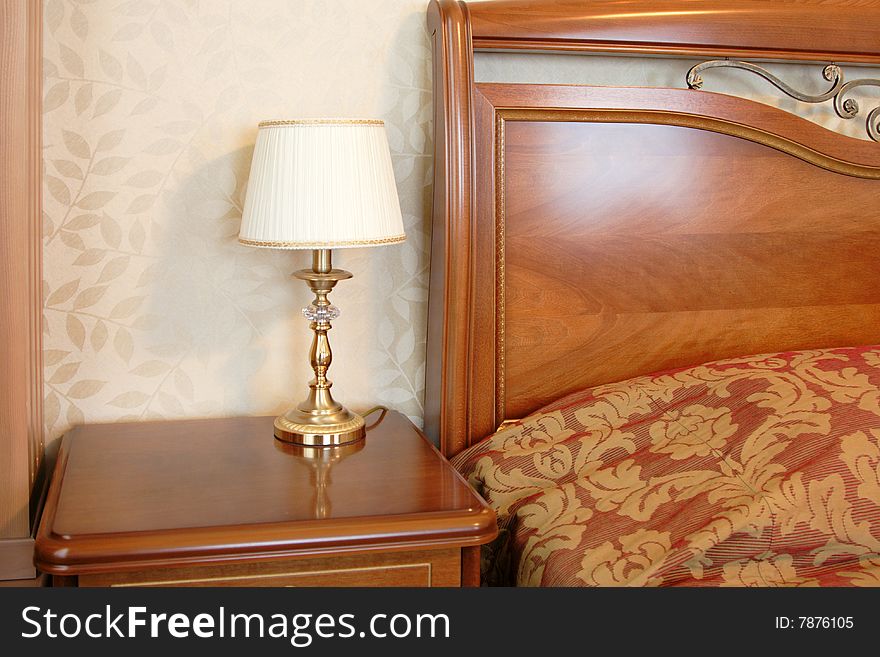 Golden classic lamp on the table near the bed in suite