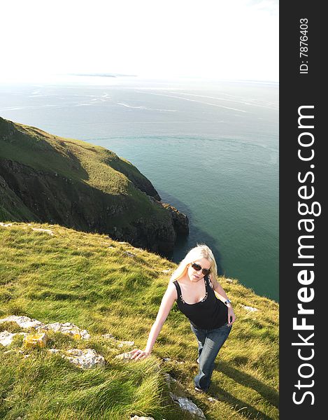 Female model climbing up the cliffs on a sunny day with a glorious setting on the sea. Female model climbing up the cliffs on a sunny day with a glorious setting on the sea