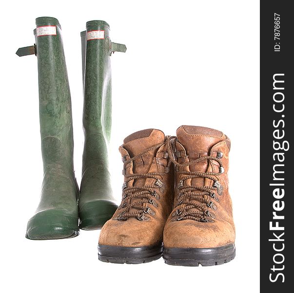 Old walking boots and green Wellington boots isolated against a white background