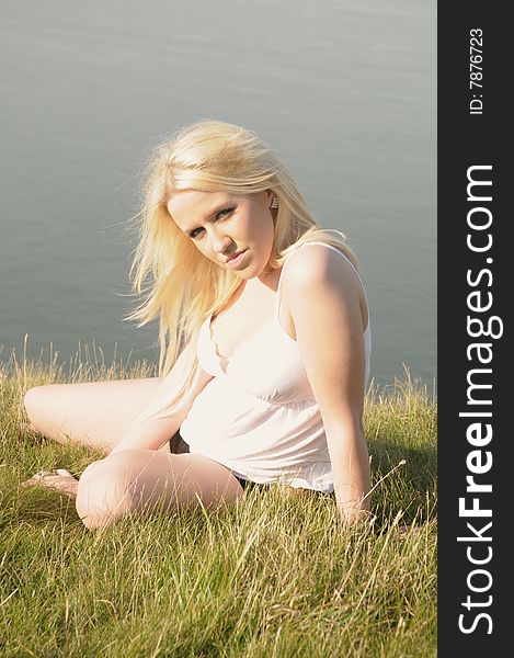 Female model sitting on the top of cliffs in the grass with the sea behind her. Female model sitting on the top of cliffs in the grass with the sea behind her