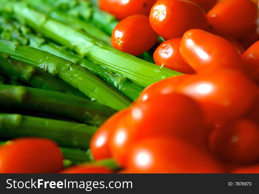 A close up image of ripe vibrant asparagus and cherry tomatoes. A close up image of ripe vibrant asparagus and cherry tomatoes