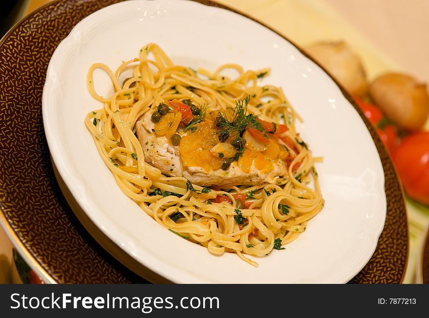 An image of a chicken pasta dish with capers and garnish