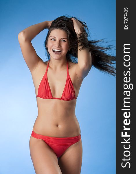 Image of a bright brunette in a red bathing suit on a blue background