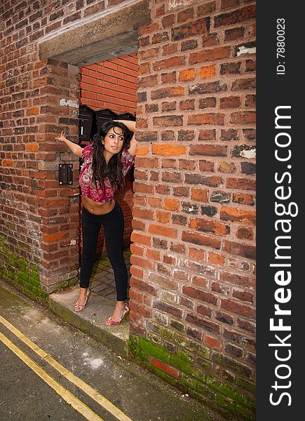 A sexy young Asian female posing in the doorway of a city center building.