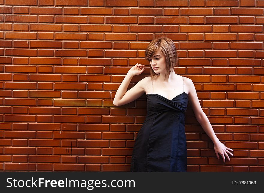 Young woman portrait posing over red brickwall