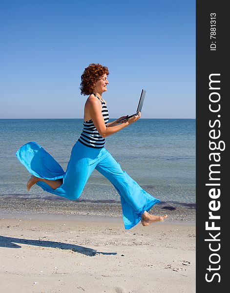 Girl with laptop running along sea coast. Girl with laptop running along sea coast