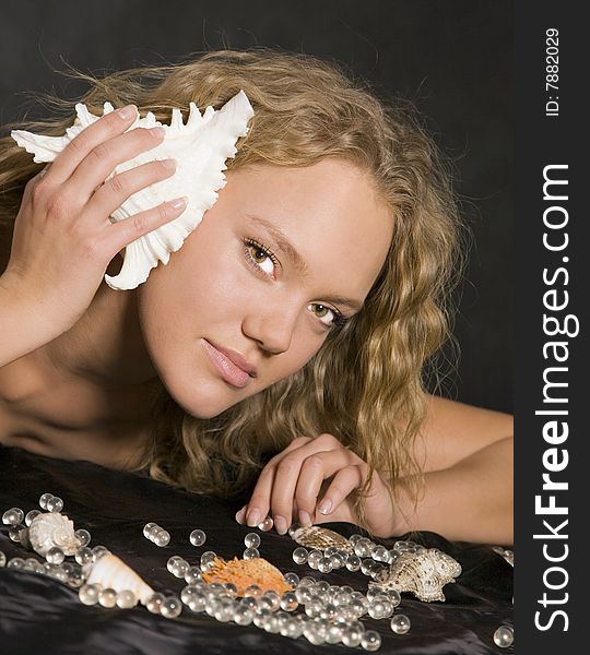 Pretty young woman with ocean shell to her ear. Pretty young woman with ocean shell to her ear