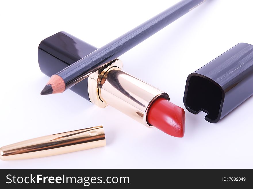 Red lipstick and black crayon on white background