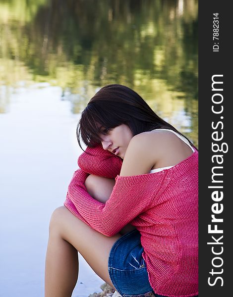 Young thoughtful woman against water background.