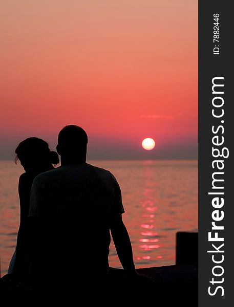 Two people sitting at the beach and watching sunset. Two people sitting at the beach and watching sunset