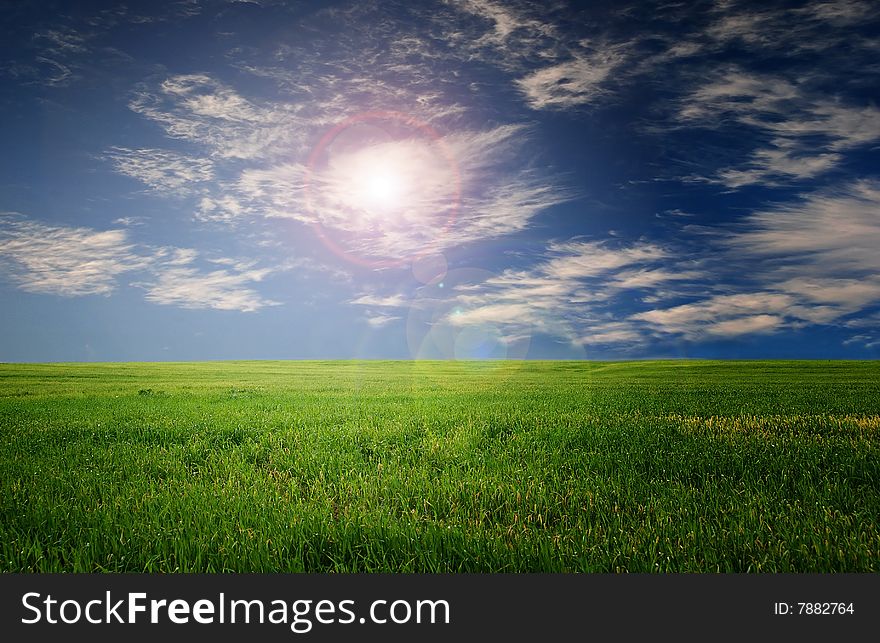 Beautiful view of a green grass field with cloudy blue sky. Beautiful view of a green grass field with cloudy blue sky