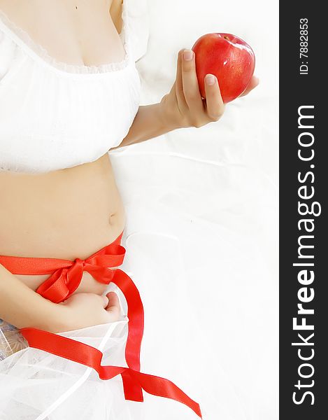 Woman hands holding pregnant belly over white with red apple and ribbon. Woman hands holding pregnant belly over white with red apple and ribbon