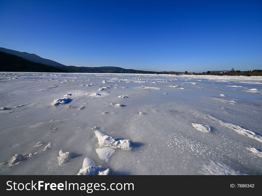 Frozen lake with wind-blown snow on the surface. Copy space.