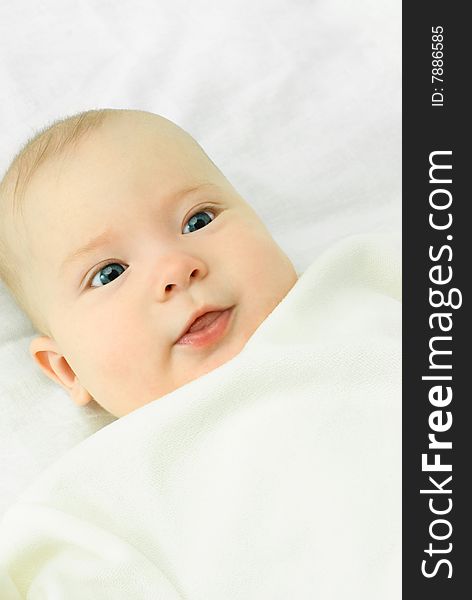 Portrait of a cute four months old baby boy on the bed with white sheets