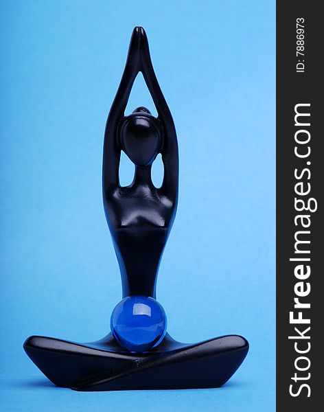 Figurine of the meditating woman on a blue background