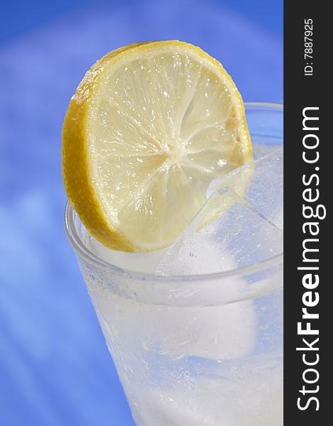 Lemon slice resting in glass of ice water. Lemon slice resting in glass of ice water