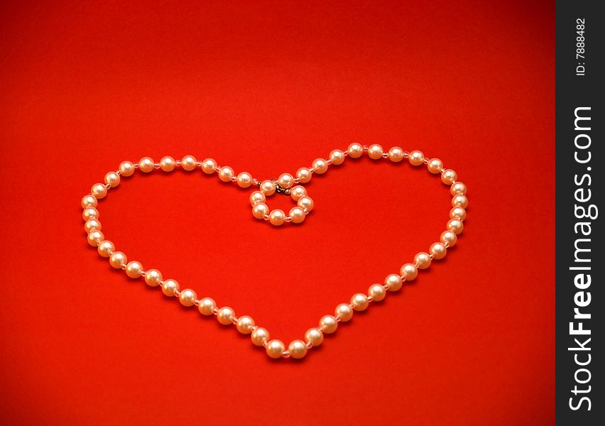 Heart Made Of Pearl Necklace On Red Background