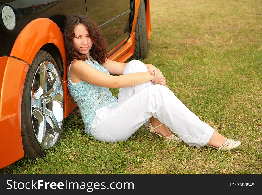 Girl sits on green grass near car. Girl sits on green grass near car