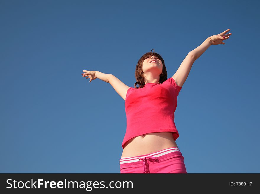 Young girl with raised hands on blue sky background