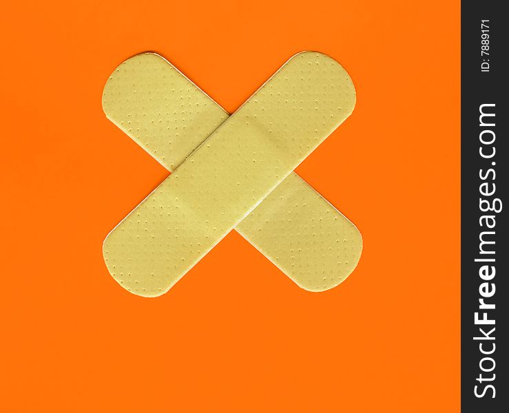 Two plasters forming a cross on orange background