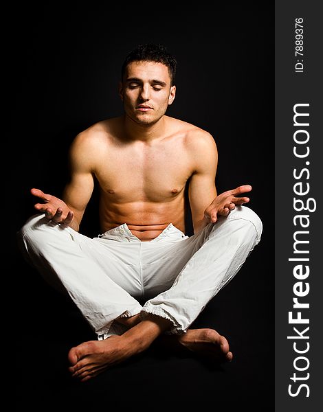 Young man in yoga position on black background. Young man in yoga position on black background