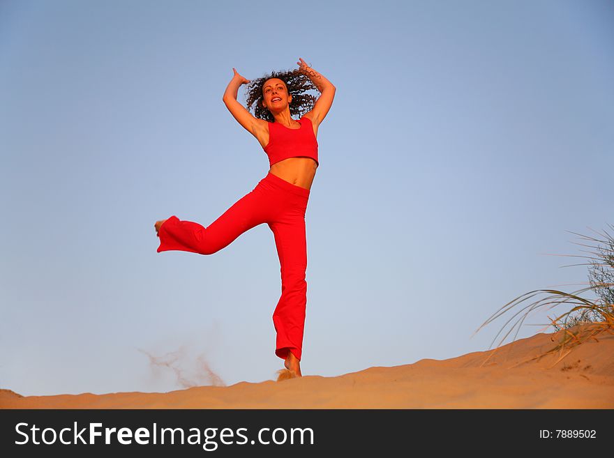 Young woman in red runs on sand. Young woman in red runs on sand