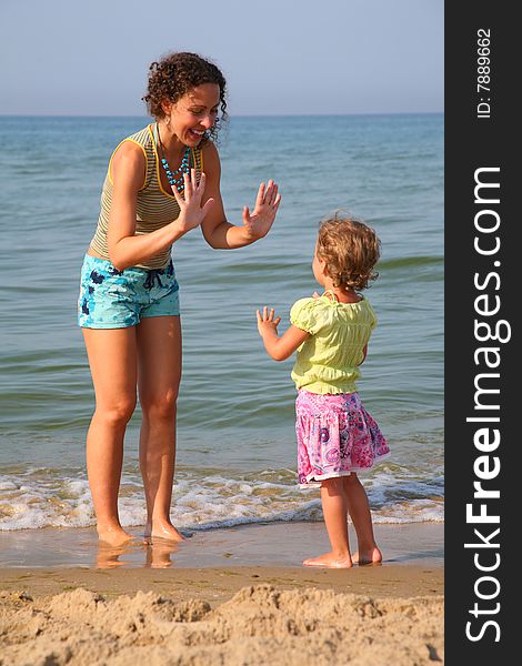 Mother plays with daughter on beach, okee-dokee