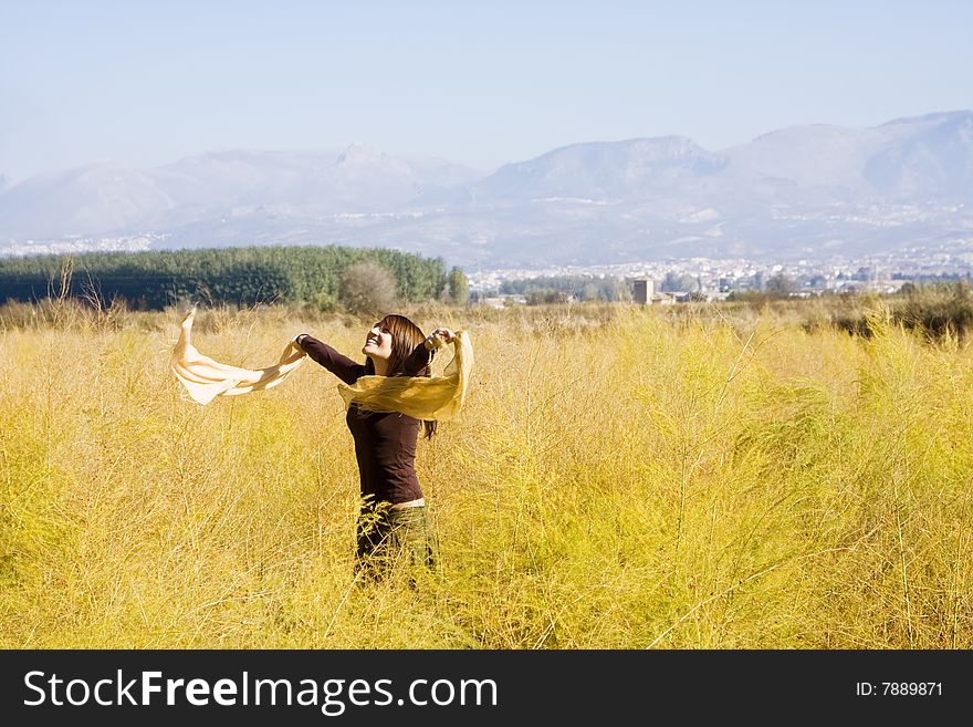 Young woman dancing with scarf in a field. Young woman dancing with scarf in a field.