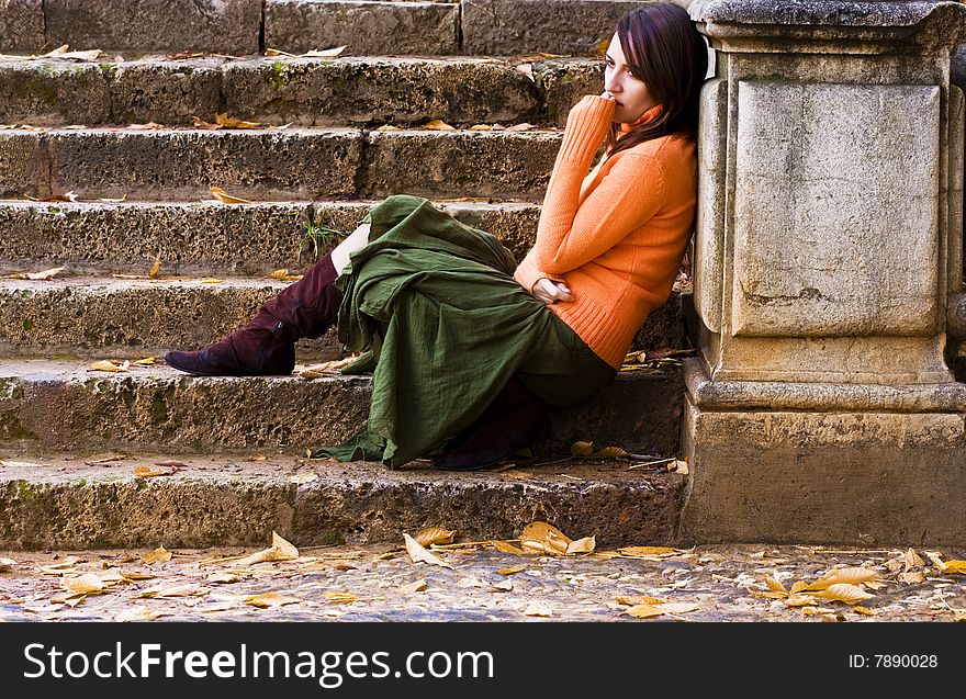 Young thoughtful woman sitting in stone stairs.