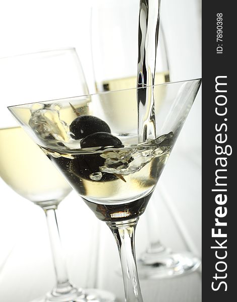 Pouring white wine into a glass where has black olive inside. Pouring white wine into a glass where has black olive inside.