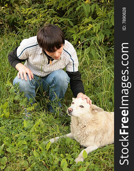 Fellow caresses by hand dog in  grass