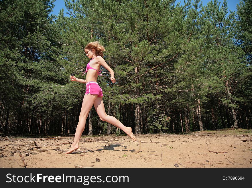 Young girl runs on sand in wood. Young girl runs on sand in wood