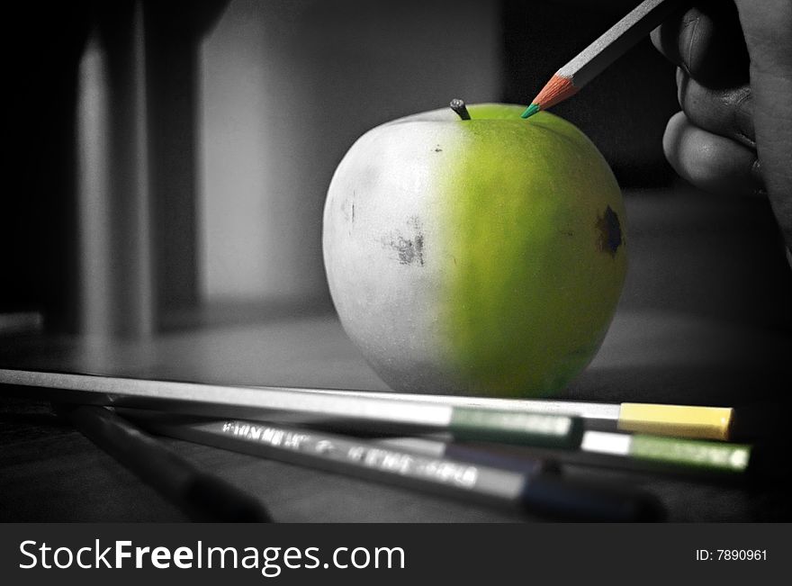 Black and white picture of an apple with a pencil adding color. Black and white picture of an apple with a pencil adding color
