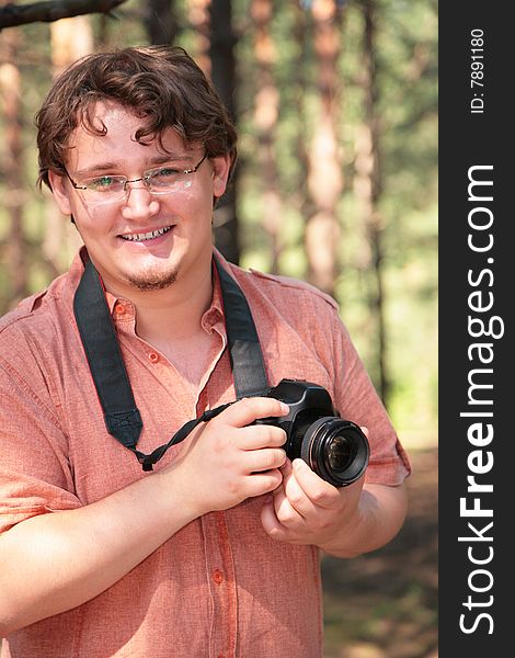 Smiling photographer with camera in wood