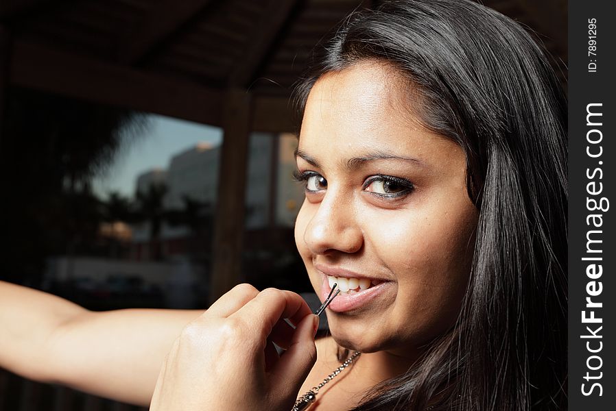 Young woman smiling while holding a hair pin in her mouth