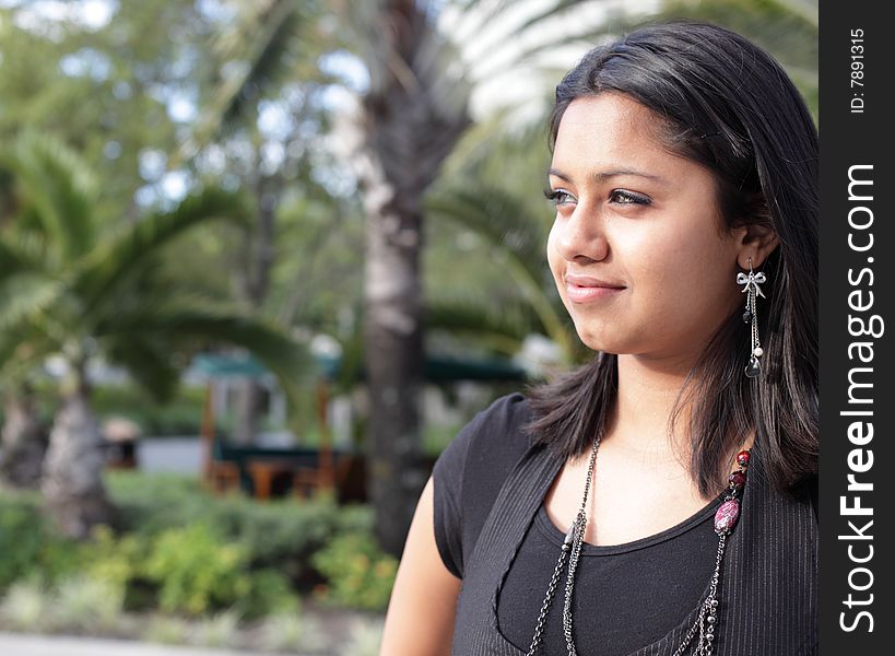 Young woman outside smiling and looking away from the camera. Young woman outside smiling and looking away from the camera