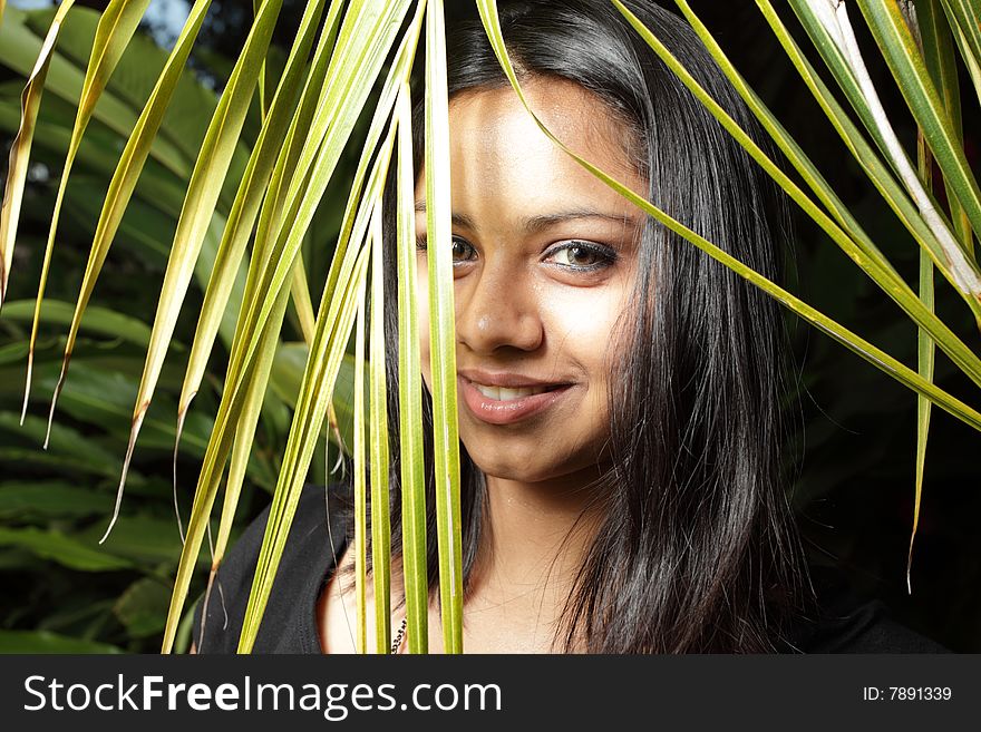 Beautiful woman behind a palm frond. Beautiful woman behind a palm frond