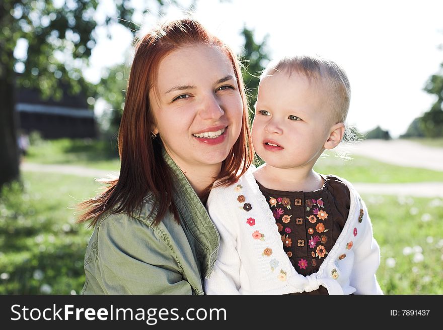 Portrait of a young tender mother with her little daughter during their walk in park in sunny summer day. Portrait of a young tender mother with her little daughter during their walk in park in sunny summer day
