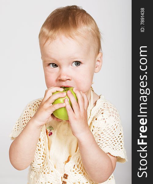 Studio portrait of a little girl eating an apple