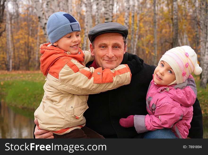 Grandfather with children in autumnal park