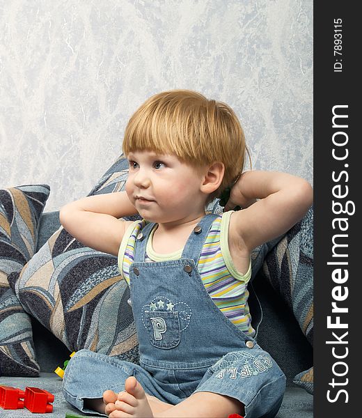 The little boy sits on a sofa. The little boy sits on a sofa