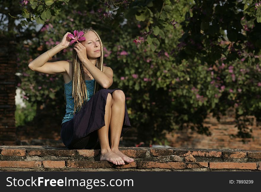 A girl attaching a pink flower to her hair. A girl attaching a pink flower to her hair