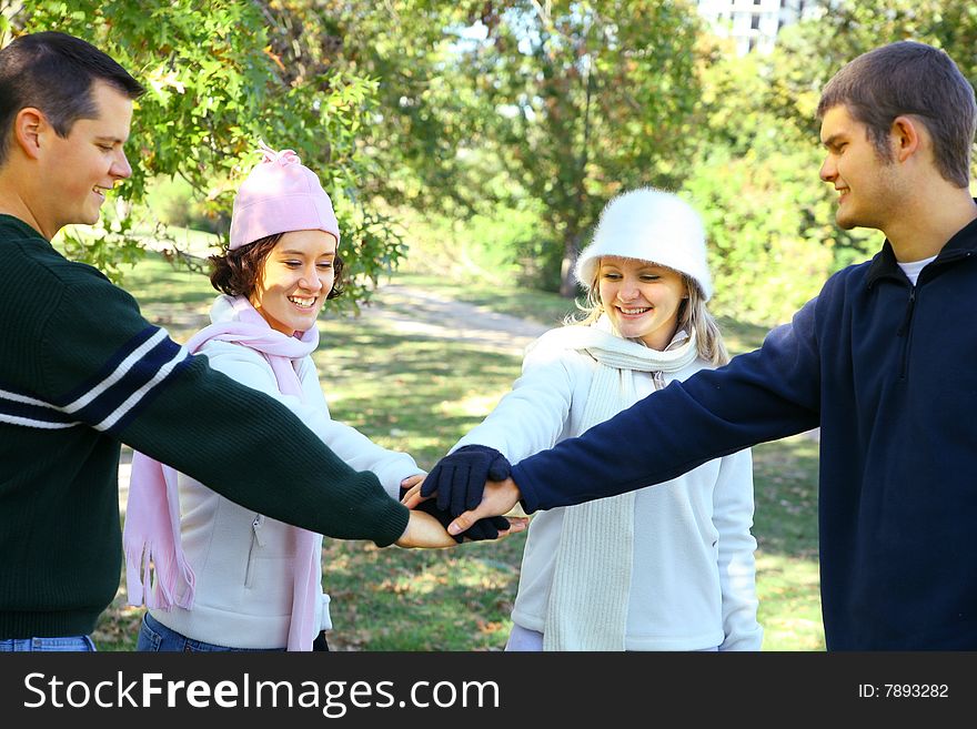 Four young male and female friends join hands in park environment. concept for unity. Four young male and female friends join hands in park environment. concept for unity