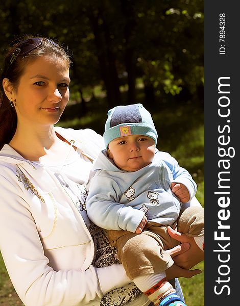 Portrait of a young beautiful mother holding her child, taken in park in sunny summer day. Portrait of a young beautiful mother holding her child, taken in park in sunny summer day