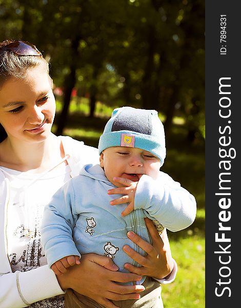 Portrait of a young beautiful mother holding her child, taken in park in sunny summer day. Portrait of a young beautiful mother holding her child, taken in park in sunny summer day